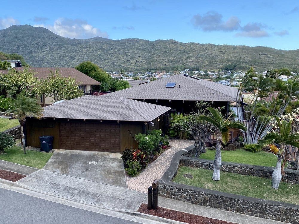 Aerial view of a modern home with a landscaped yard and mountains in the background.
